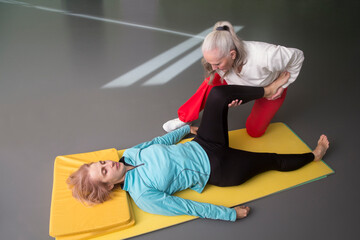 Senior woman trainer conducts somatic gymnastics for another woman in a gym. Somatic training - a...