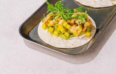 Fresh taco with chicken, mango, and herbs on a metal tray