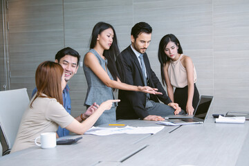 Colleagues engage in a collaborative meeting, analyzing data and discussing project details. Their teamwork, mixed perspectives, and setting reflect a dynamic and goal-driven business atmosphere.