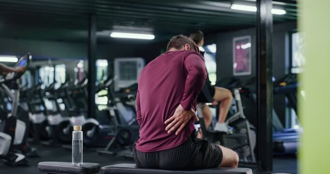 Gym, athlete and man with back pain, fitness and training injury after exercise routine and burnout. Workout, accident and person with muscle sprain, massage and joint tension in health club or sore