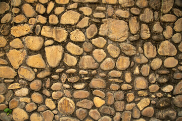 Rustic stone wall texture with natural river rocks, earthy tones and organic pattern. Rough masonry background ideal for architecture, construction, heritage design, and nature-inspired textures.”
