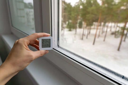 High indoor humidity indicated by a digital hygrometer showing 79 percent, next to a wet window with visible condensation in winter, indoor climate control concept. - Powered by Adobe