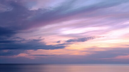 Fototapeta premium Beautiful landscape photograph of a sunset over the ocean. the sky is filled with vibrant colors of pink, purple, and blue, with a few wispy clouds scattered across the horizon.