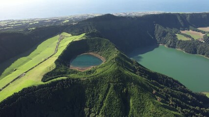 Sete Cidades crater with Lagoa Rasa and Lagoa Verde revealed as the view moves left and opens toward the ocean on Sao Miguel island in the Azores