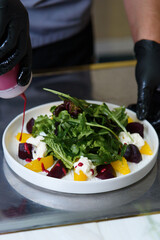the chef prepares a salad with beetroot, oranges, strachatella cheese and flax seeds