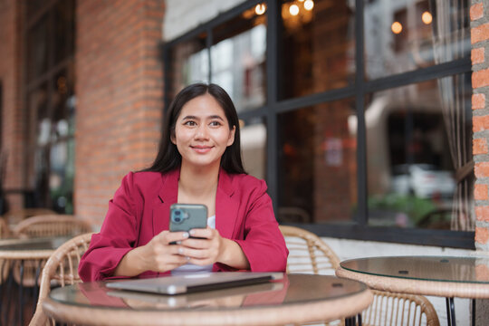 Young asian woman holding smartphone at cafe table
