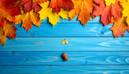 Autumn leaves on blue wooden background with acorn.