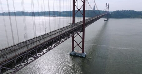 Half marathon and 10K long distance running event in Lisbon, Portugal, Europe. Runners crossing the iconic famous red 25th April suspension bridge by Cristo Rei. Tagus river aerial drone shot