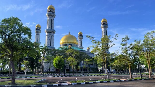 The golden dome and building of the Jamil Asra Hassan Al-Bolkiah Mosque in Bandar Seri Bagawan, Brunei Darussalam, are framed by tropical palm trees on a sunny day. Asia. 4К