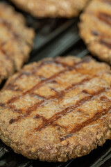 Close-up view of a juicy grilled beef patty with char marks on a hot grill. Ideal for barbecue, cooking, meat, and food industry concepts.