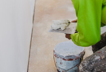 Worker with wall plastering tools renovating house.