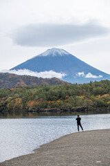 Saiko Lake, Saiko, Fujikawaguchiko, Minamitsuru District, Yamanashi, Japan Person standing by lake with view of Mount Fuji in autumn landscape