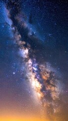 A breathtaking long-exposure photograph captures the brilliant, glowing band of the Milky Way galaxy against a dark, star-filled night sky above a warm horizon.
