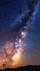 A breathtaking vertical night sky photograph capturing the vibrant core of the Milky Way galaxy above a dark terrestrial silhouette.
