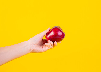 Red apple in hand yellow background