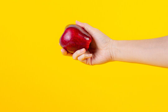 Red apple in hand yellow background
