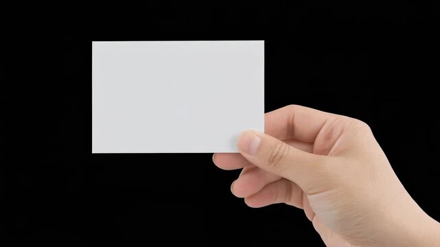 Close up on hand holding a blank white card with space for text isolated against black background ready to be personalized.