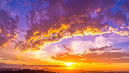 Dramatic sunset illuminating rugged mountain silhouettes with vibrant orange and purple clouds.