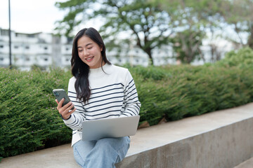 Young woman connecting using phone and laptop outdoors