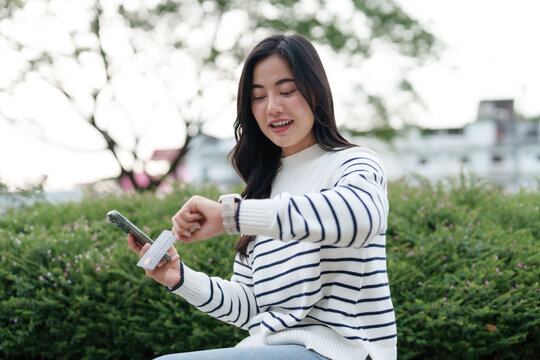 Young woman making mobile payment using smartphone and smartwatch
