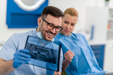 Dentist shows dental X-ray to patient in modern clinic