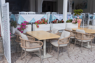 Charming Mediterranean-style cafe terrace with wicker chairs, wooden tables, and colorful flower