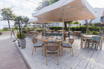 Modern outdoor cafe table with wicker chairs and green plants