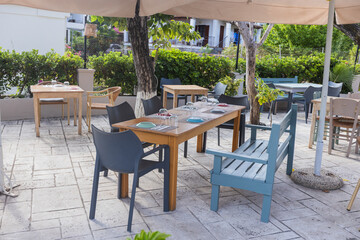 Modern outdoor cafe table with wicker chairs and green plants