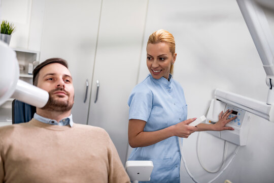 Patient undergoing dental checkup with smiling dentist in modern clinic setting during daylight hours - Powered by Adobe