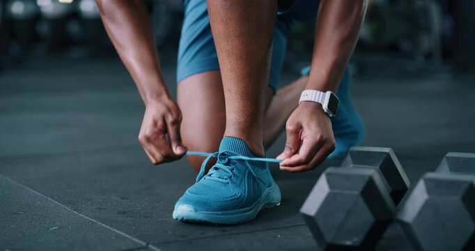 Person, hands and tying with shoes in gym for fitness, workout preparation or start exercise. Closeup, active or getting ready with tie, sneaker or laces for indoor training or run in health club