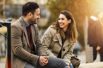 Couple enjoys cheerful conversation in city park during sunny afternoon