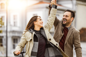 Couple joyfully dancing together in a city street during a sunny afternoon