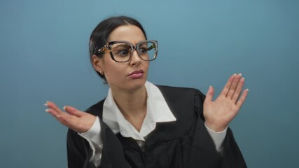 Hispanic woman judge in black uniform with hands raised, expressing surprise against isolated blue background. - Powered by Adobe