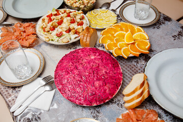 A table with a variety of food including a red pie, bread, and oranges