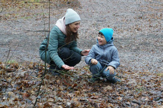 Joyful mother and son laughing together while exploring an autumn forest