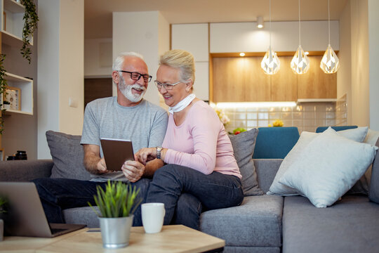 Senior couple enjoying time together while looking at a tablet in their cozy living room