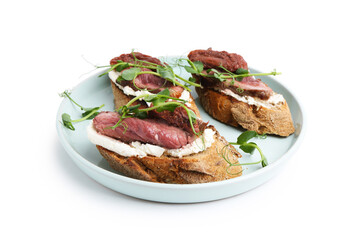 Delicious bruschettas with roast beef, cream cheese, sun-dried tomatoes and microgreens isolated on white