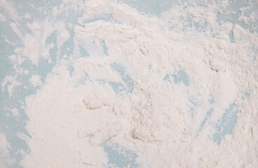 A white powdery substance is scattered on the blue surface. This is flour