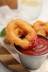 Deep fried squid rings with ketchup on white table, closeup