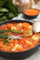 Tasty lentil soup served on grey table, closeup