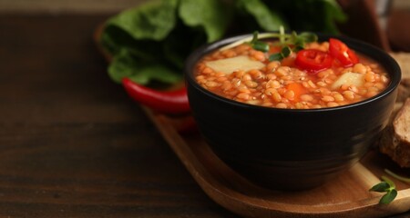 Delicious lentil soup with vegetables served on wooden table, closeup. Space for text