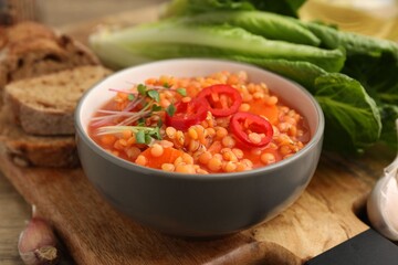 Delicious lentil soup with vegetables served on table, closeup
