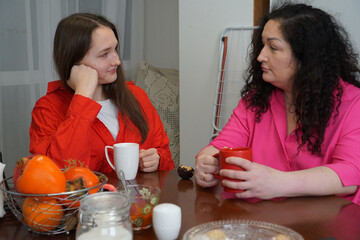 Mother and daughter having a heartfelt conversation over coffee at a dining table.