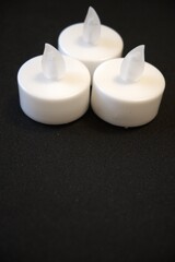 3 white electric candles on a black background with Copy Space in natural condition.