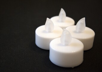 4 white electric candles on a black background with Copy Space in natural condition.