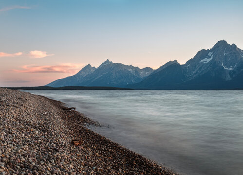 Pebble beach along shore of Jackson Lake, Tetons in the distance