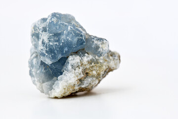 Fototapeta premium Close-up studio shot of a raw, light blue Celestine (Celestite) mineral specimen with crystals embedded in tan and white rock matrix, isolated on a white background. This image is perfect for geology.