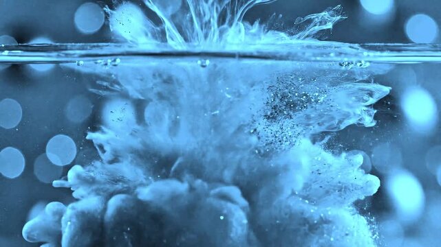 Luxury background of blue ust particles flowing in the liquid with slow motion and bokeh. Abstact elegant blue background. blue particles fluid motion. Liquid motion, ink drops mixing in water. 