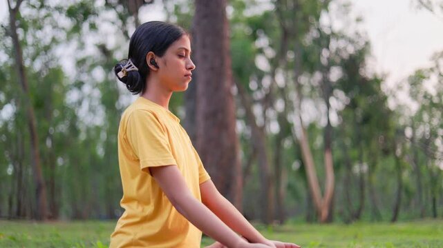 Fit young woman in lotus position meditating outdoor in early morning, embracing calmness and self-awareness.