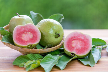 Fresh red guava, a vibrant tropical fruit displayed with leaves on a natural green background perfect for healthy food and tropical lifestyle themes.